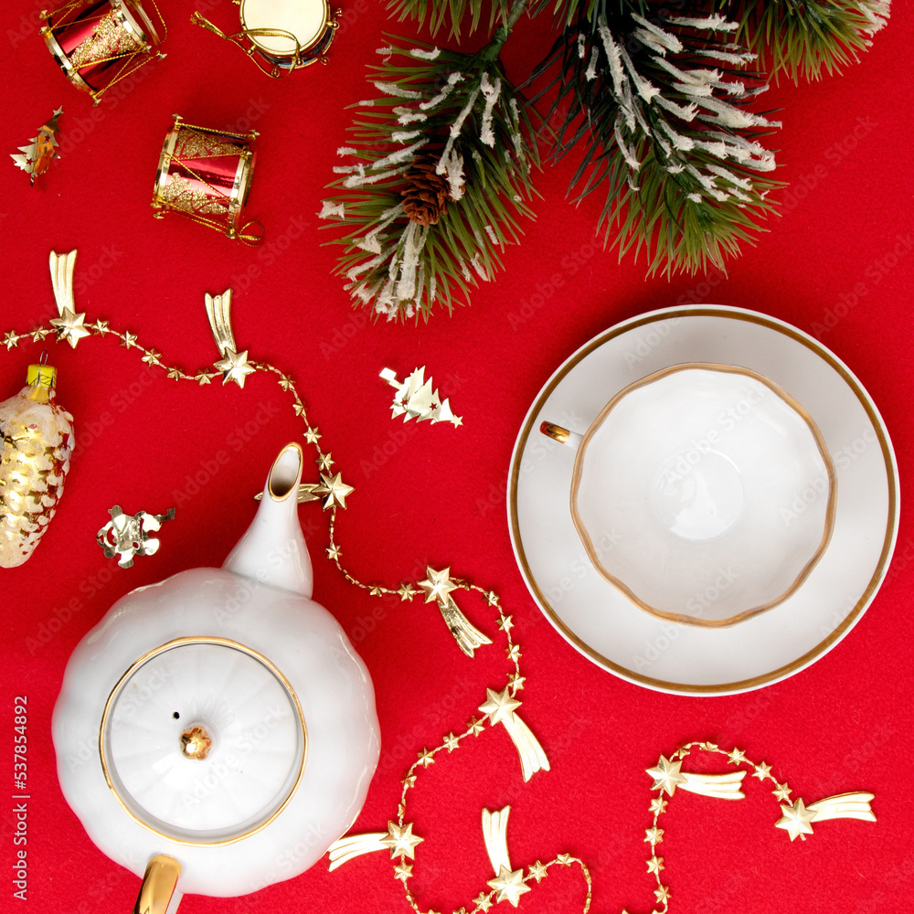 New Year's composition. New Year and Christmas. A spruce branch, a cup and a kettle on a red background. View from above. Minimalism New Year's composition. New Year and Christmas. A spruce branch, a cup and a kettle on a red background. View from above. Minimalism