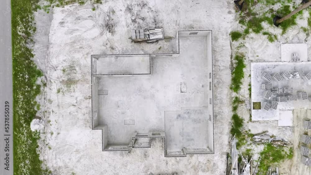 Aerial view of unfinished frame of private house with brick concrete walls ready for mounting wooden roof beams under construction Aerial view of unfinished frame of private house with brick concrete walls ready for mounting wooden roof beams under construction