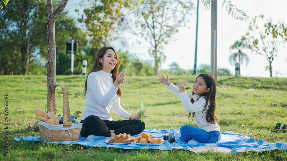 Happy asian family mother and her daughter in the garden, They are having fun playing and blowing bubbles. Family enjoying sunny fall day in nature. Happy asian family mother and her daughter in the garden, They are having fun playing and blowing bubbles. Family enjoying sunny fall day in nature.