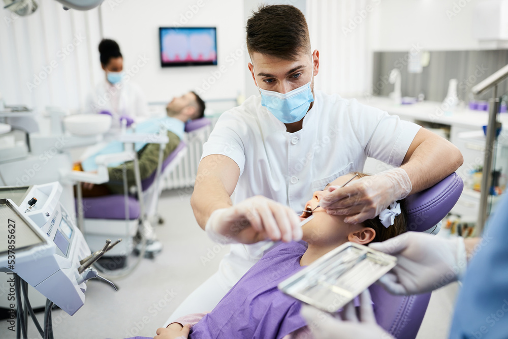 Young dentist examining teeth of little girl at dental clinic. Young dentist examining teeth of little girl at dental clinic.