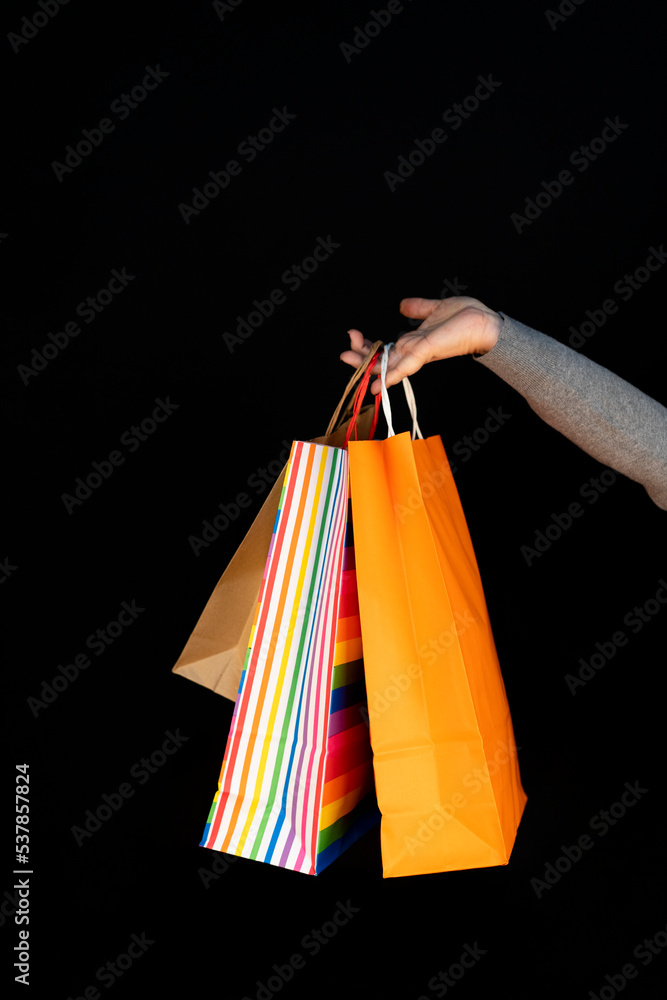 Shopping bags in the woman hands. Joy of consumption. Purchases, black friday, discounts, sale concept. Black background..