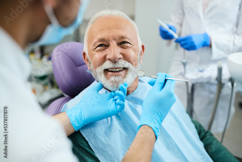 Happy senior man having dental treatment at dentist's office. photo