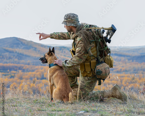 Soldier with a dog. Infantryman shows his dog the direction and gives the task.