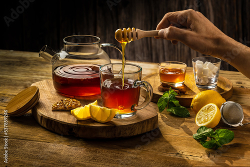 thé chaud main servant du miel théière citron et menthe pot de miel et cuillère à miel  photo