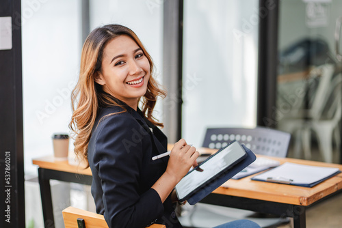 Fotografie Asian businesswoman holding a tablet in hand looking at the camera Young woman c