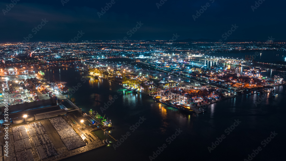 aerial view international shipping port load and unloading container by crane onto transport ships and trailer for import export distributing products to customers and consumer over lighting aerial view international shipping port load and unloading container by crane onto transport ships and trailer for import export distributing products to customers and consumer over lighting