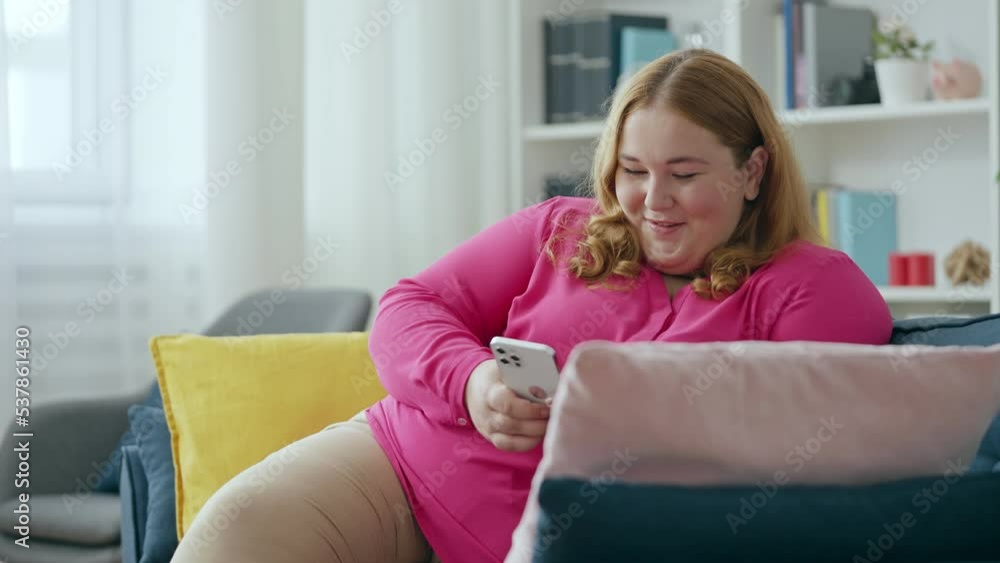 Flirty body positive female chatting in dating app on smartphone and smiling Flirty body positive female chatting in dating app on smartphone and smiling