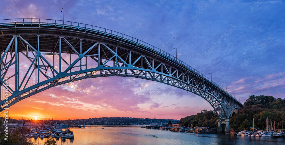 Fototapeta premium The sun rises over Lake Union, chasing away the last vestiges of blue in the sky. A bridge spans across the foreground
