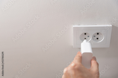 a man inserts a charger from the device into a white socket