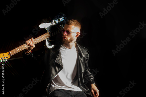Εκτύπωση καμβά A cheeky rocker in a leather jacket and pink glasses slung a guitar over his shoulder
