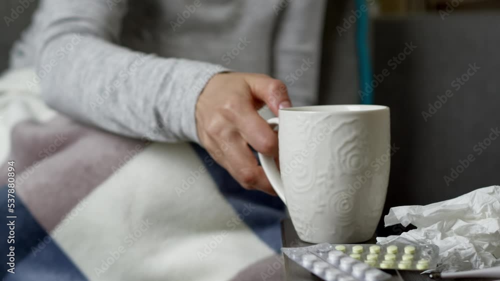 The concept of illness with a cold, runny nose. A cup of warm tea in the hands of a woman. Close-up. Flu. The concept of illness with a cold, runny nose. A cup of warm tea in the hands of a woman. Close-up. Flu.