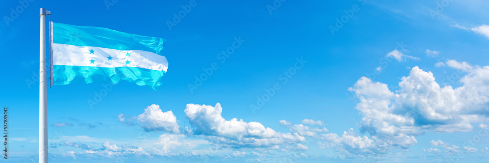 Honduras flag waving on a blue sky in beautiful clouds - Horizontal banner