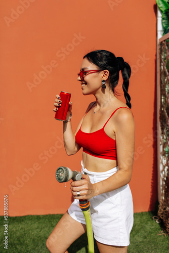 A girl on an orange background with a red tin can in her hands. Cheerful girl, advertising shooting
