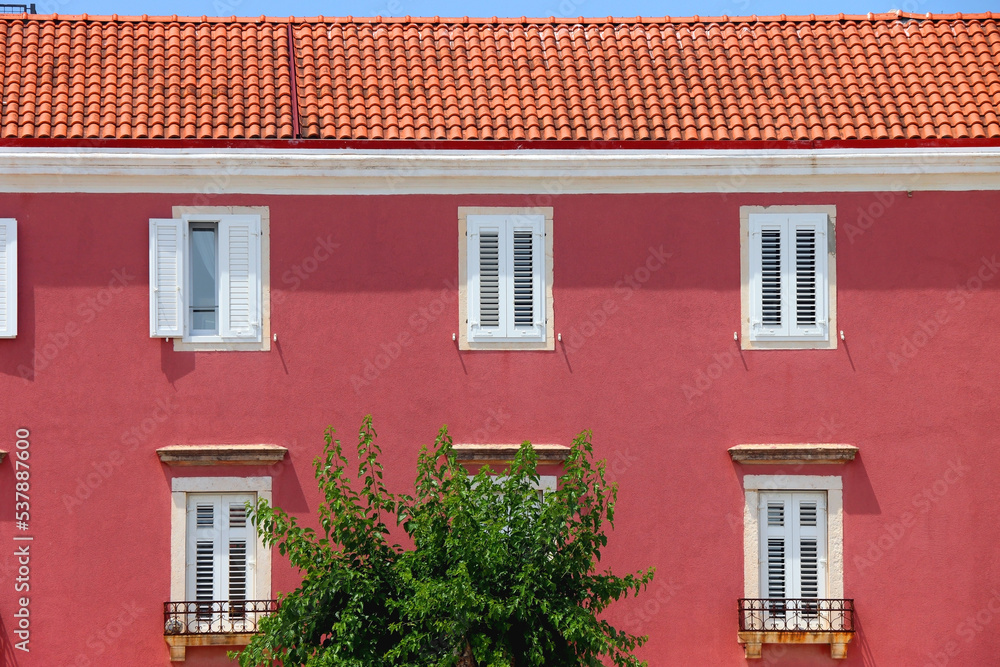 Traditional mediterranean building with pink facade and white windows. Traditional architecture in Supetar, island Brac, Croatia.