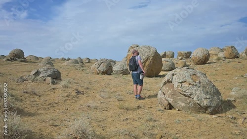 Man with backpack walking around the valley with sphere stones in Kazakhstan. 4k footage UHD 3840x2160 