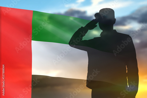 Silhouette of a solider saluting on a background of sunset and UAE flag