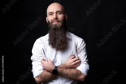 Barber with long beard and scissors on black background.