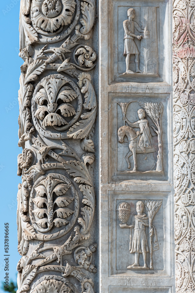 Close-up on decorative elements carved in marble pillar and wall of church in Pisa