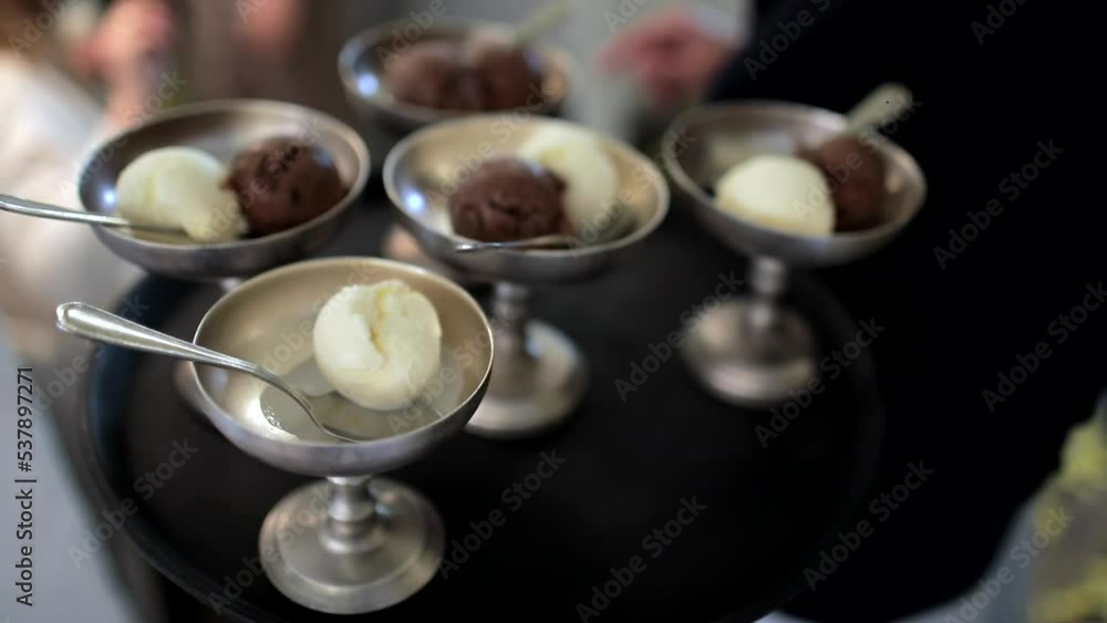 A close up of a plate with ice cream shots that the waiter carries in his hand to the guests. Appetizer buffet, buffet table. A close up of a plate with ice cream shots that the waiter carries in his hand to the guests. Appetizer buffet, buffet table.