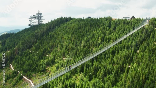 Suspension pedestrian Sky Bridge over forested canyon in Dolni Morava. Attraction leads to Sky Walk tower in mountains in Czech Republic aerial view photo