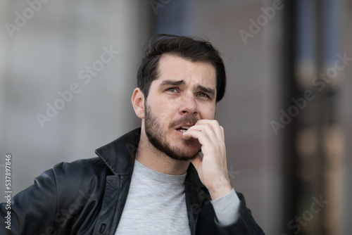 young man is nervous and bites his nails, close-up portrait