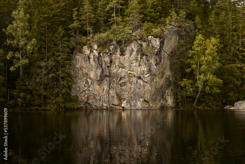 A beautiful rock formation in a forest next to a lake in summer.