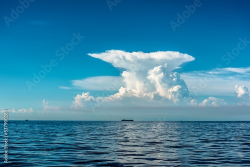 beautiful seascape with a huge mushroom cloud on the horizon, silhouette of a tanker on the horizon