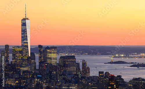 Aerial view of Lower Manhattan skyline illuminated at sunset with orange background in New York City, USA