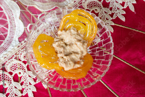 Home Made Jalebi with mishti doi or dahi in transparent glass bowl with beautiful pink background.  Traditional sweet for festival season. photo