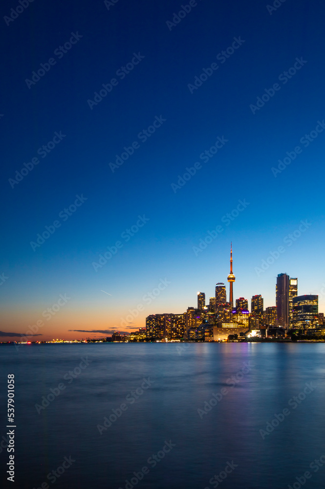 CN Tower and Toronto skyline with lake reflection during sunset or golden hour, city light after sunset