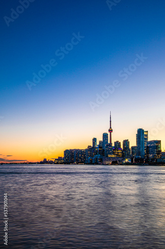 CN Tower and Toronto skyline with lake reflection during sunset or golden hour, city light after sunset