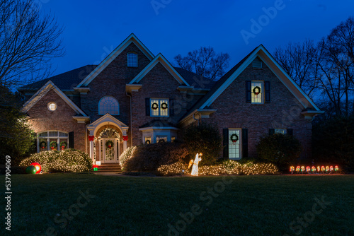 Holiday light decorations at night in front of a large brick house