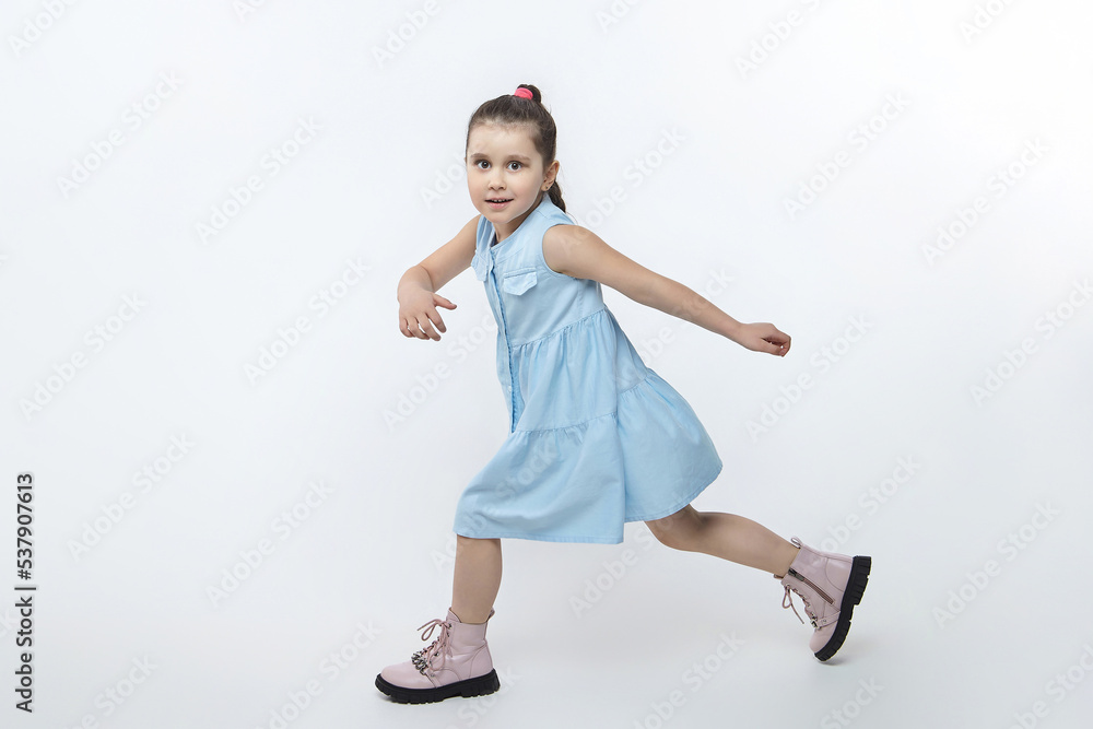 little black-haired girl in a dress and high boots runs around the studio on a white background little black-haired girl in a dress and high boots runs around the studio on a white background