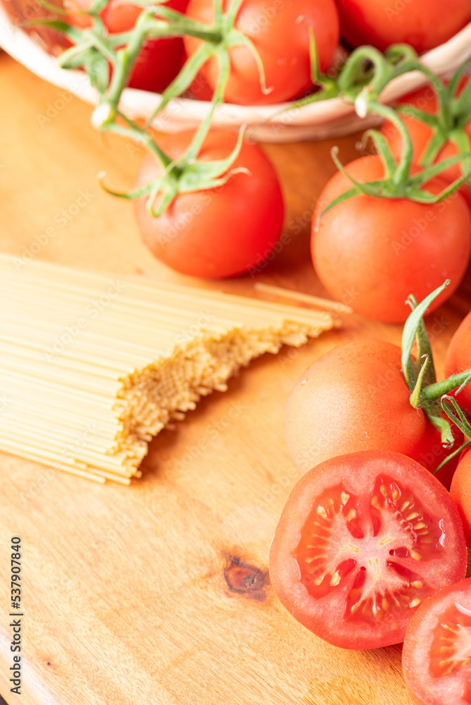 Pasta, beautiful details of red tomatoes and strands of raw spaghetti over rustic wood, selective focus. Pasta, beautiful details of red tomatoes and strands of raw spaghetti over rustic wood, selective focus.