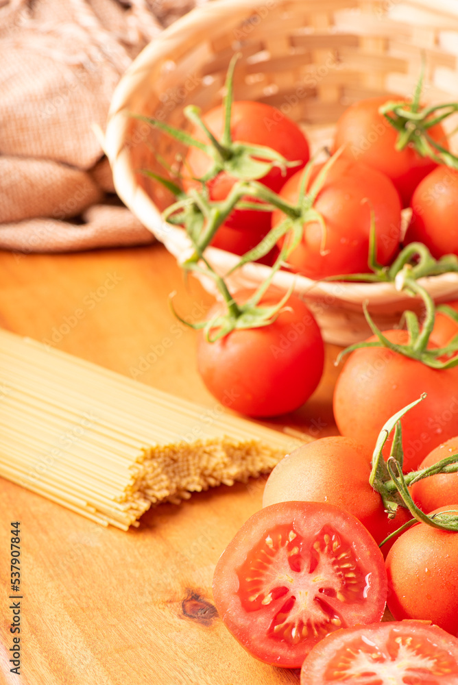 Pasta, beautiful details of red tomatoes and strands of raw spaghetti over rustic wood, selective focus. Pasta, beautiful details of red tomatoes and strands of raw spaghetti over rustic wood, selective focus.