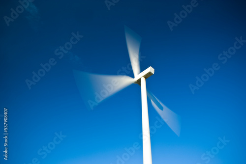 Wind turbine against a clear blue sky with motion blur blades photo