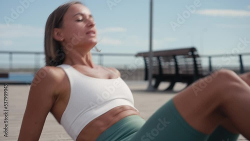 Sporty fit active young woman doing bicycle crunch situp exercise alone lying on mat wooden floor, strong sportswoman wear activewear training abs core muscles workout routine. photo