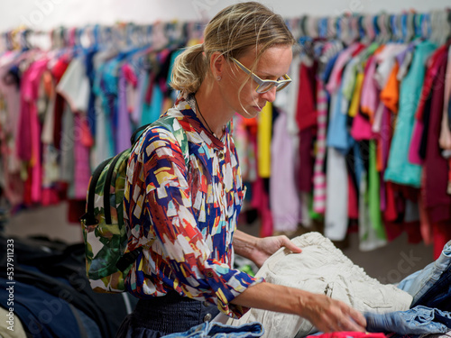 Woman choosing second hand clothes at the clothing store. Lifestyle.