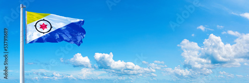 Bonaire flag waving on a blue sky in beautiful clouds - Horizontal banner photo