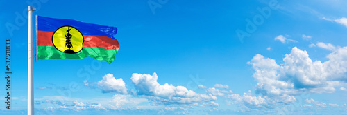 New Caledonia flag waving on a blue sky in beautiful clouds - Horizontal banner photo