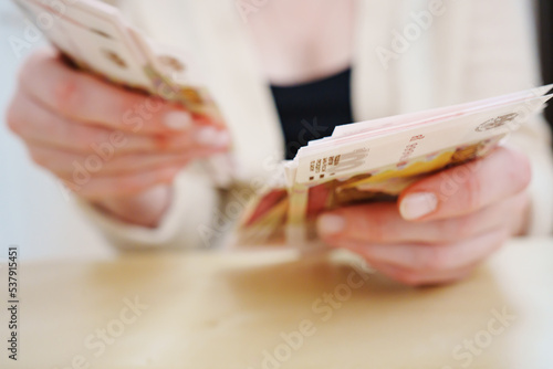 a woman holds in her hands and recalculates Russian banknotes of 100 rubles.  photo