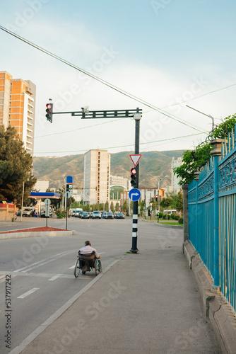 a man in a wheelchair on a highway in front of a traffic light photo