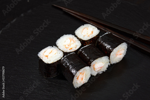 Traditional delicious freshsushi rolls with shrimp on a black background. Sushi roll with rice, cream cheese, avocado, salmon, sesame. Sushi menu. Japanese kitchen, restaurant photo