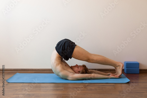 man in halasana asana photo