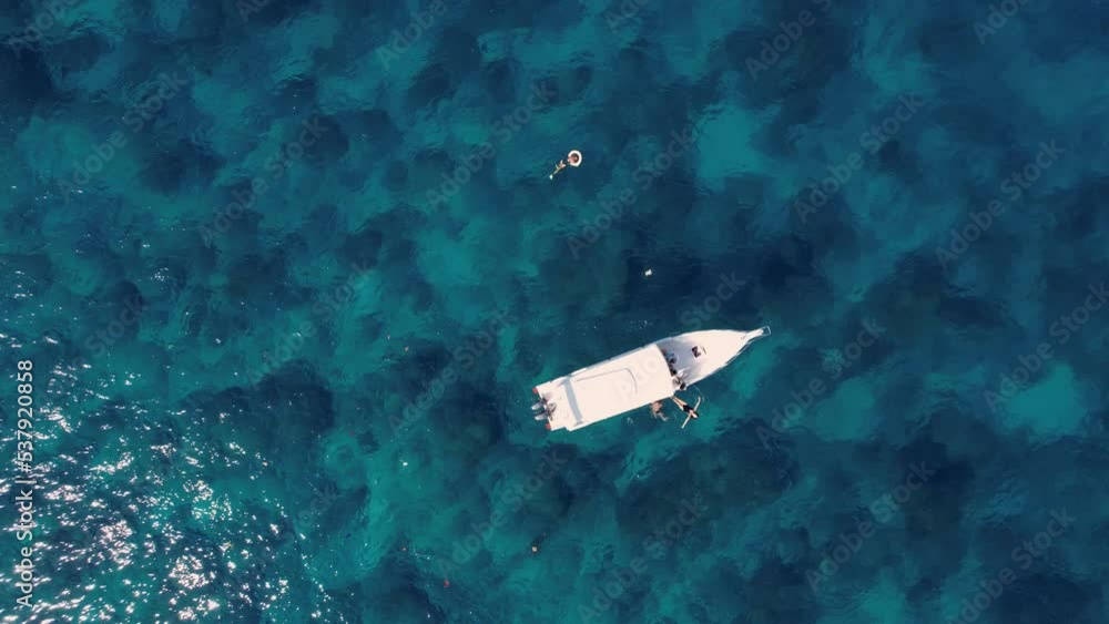 Turquoise blue water sea with speedboat and swimming tourists, aerial drone top view shot. One ship boat in nature ocean landscape. Summer holiday vacation voyage, Travel destination, tourism. Turquoise blue water sea with speedboat and swimming tourists, aerial drone top view shot. One ship boat in nature ocean landscape. Summer holiday vacation voyage, Travel destination, tourism.