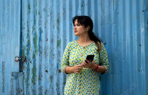 Indian woman standing on roadside with smartphone in hand photo