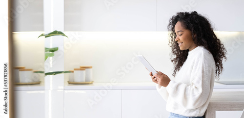 Banner African American Girl using iPad tablet at home pressing finger, reading social media internet, typing text or shopping online. Freelancer Remotely working online at home