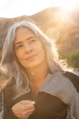Mature woman zips up dirk biking jacket in the mountains