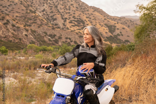 Mature woman smiling outdoors on a bike photo