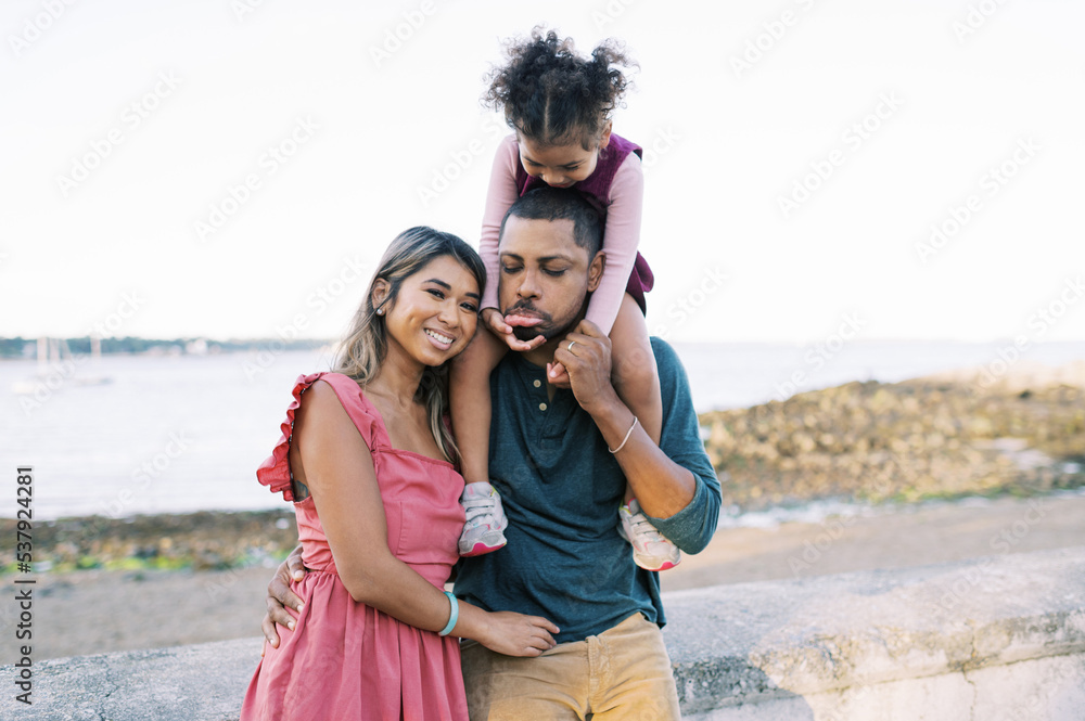 Smiling and happy multiracial family standing by the shore together Smiling and happy multiracial family standing by the shore together